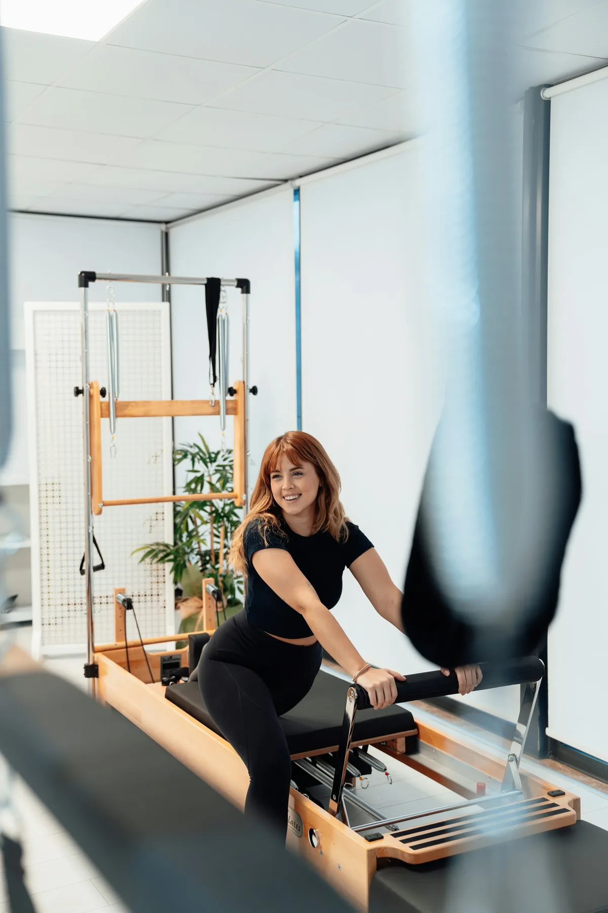 Pratiquante souriante sur un Reformer lors d’une séance de découverte