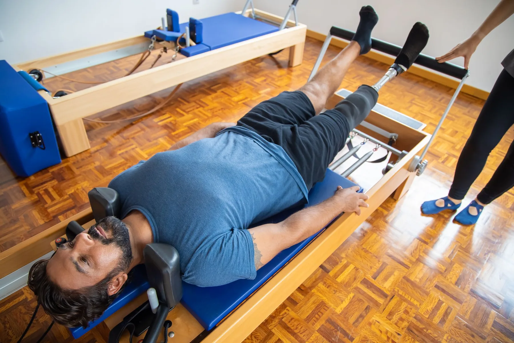 Homme allongé sur un Reformer, accompagné par une instructrice