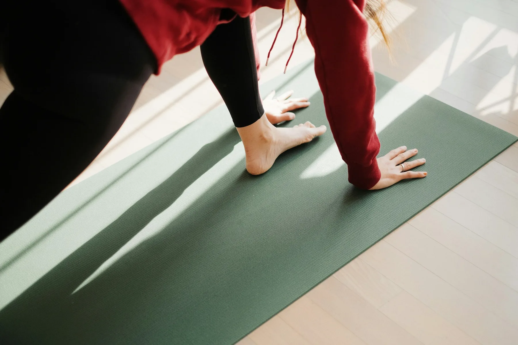 Mains et pieds posés sur un tapis vert, en posture du chien