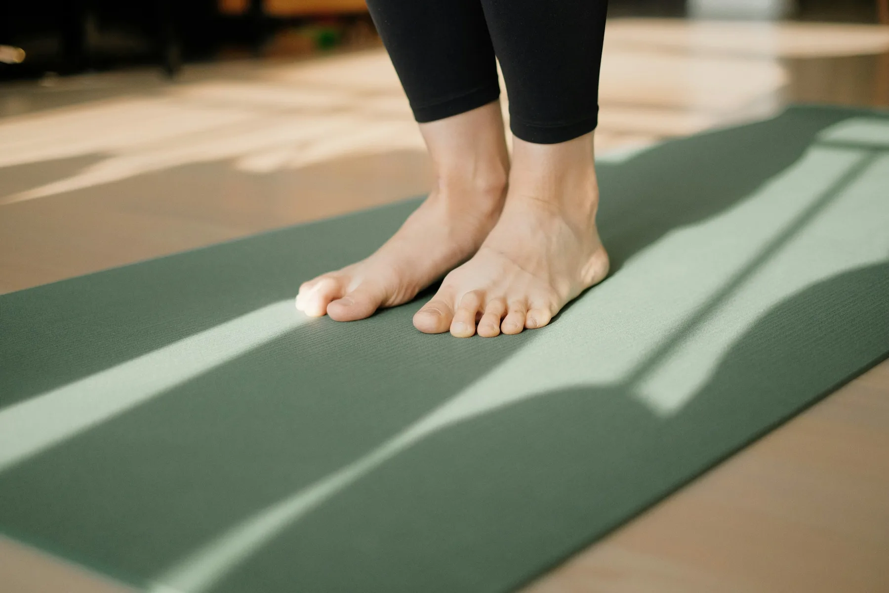 Pieds nus posés à plat sur un tapis de Pilates vert