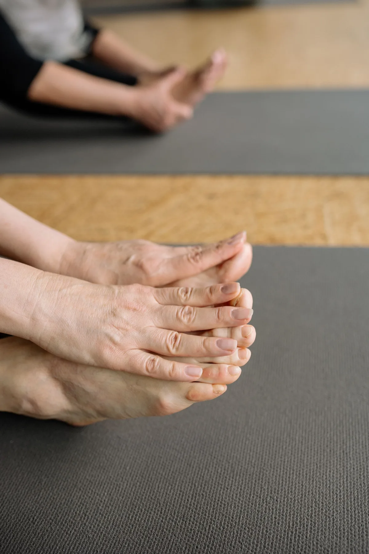 Pieds pris dans les mains, assise sur un tapis