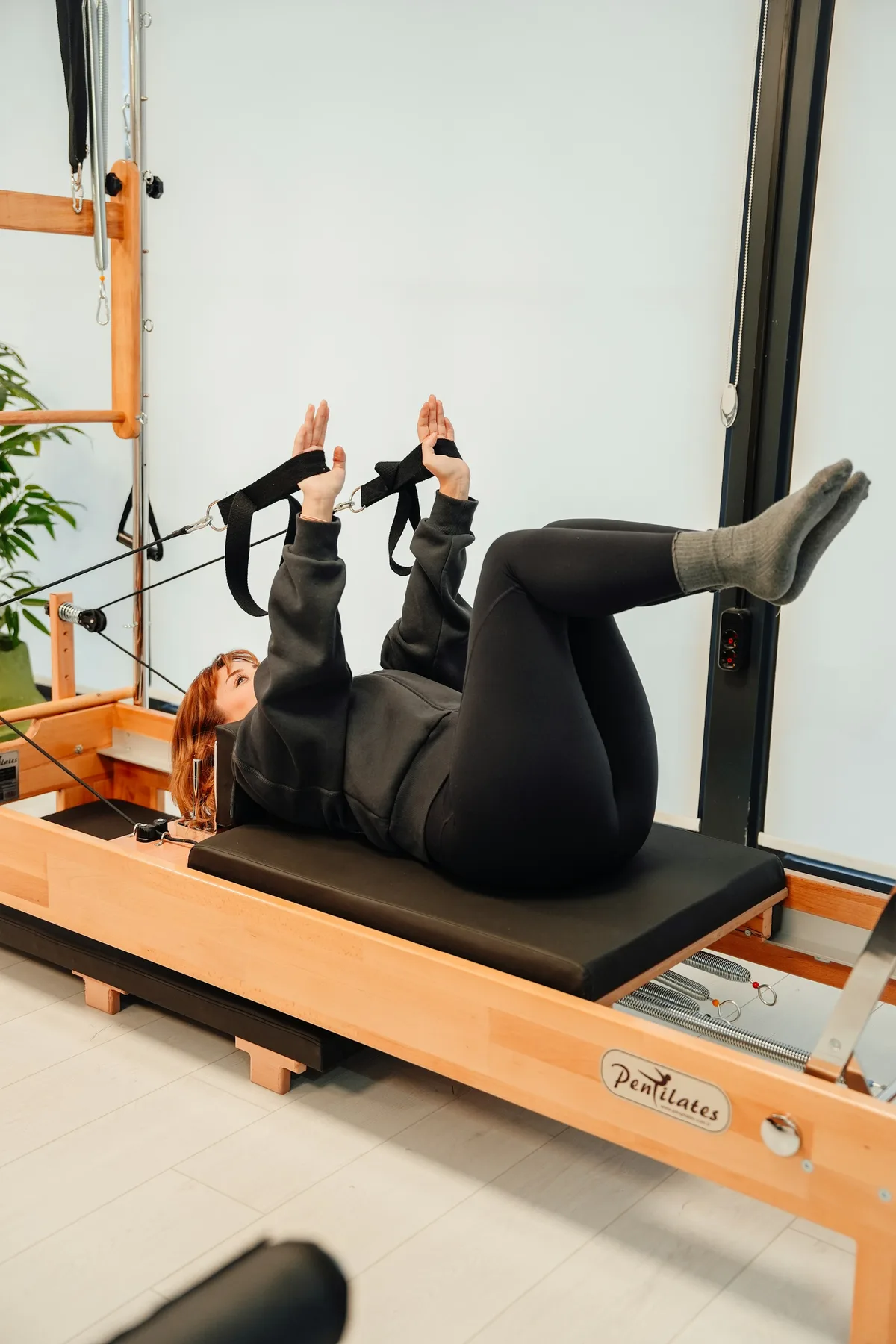 Pratiquante allongée sur un Reformer, jambes dans les sangles, nuque posée