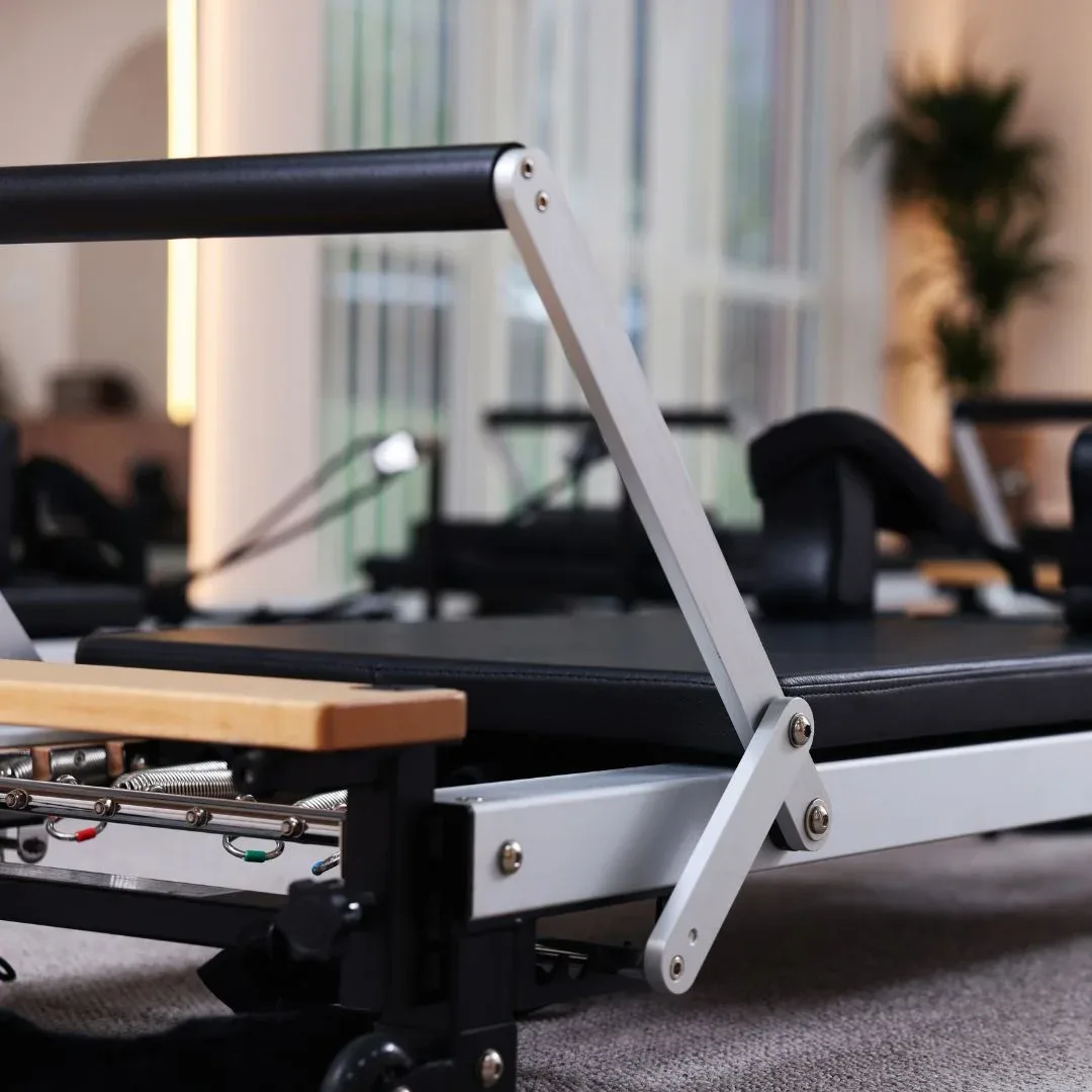 Reformer au repos en gros plan : barre de pieds, chariot et ressorts dans un studio lumineux