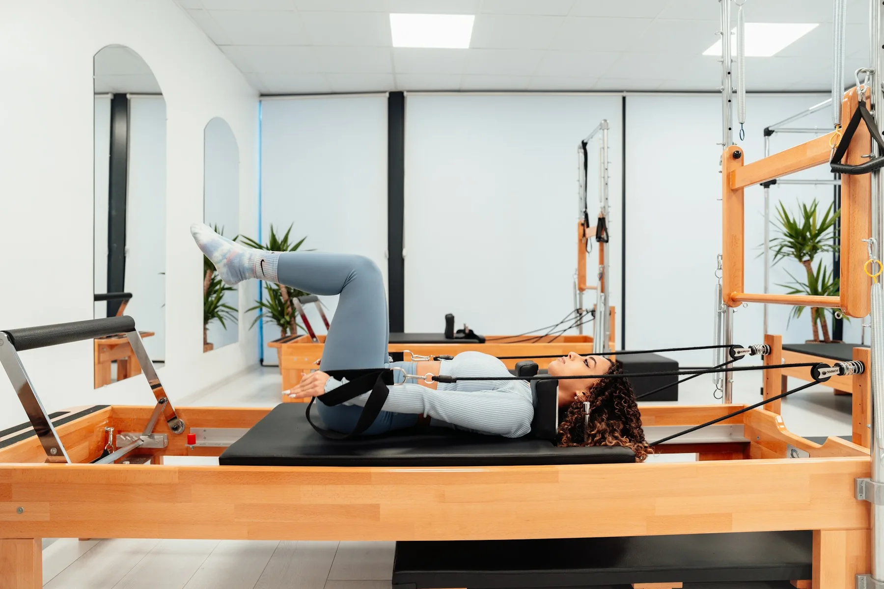Pratiquante allongée sur un Reformer, jambes dans les sangles, en respiration lente