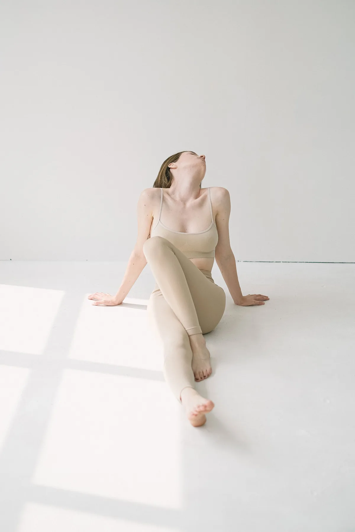 Femme assise au sol dans une pièce blanche, en respiration calme