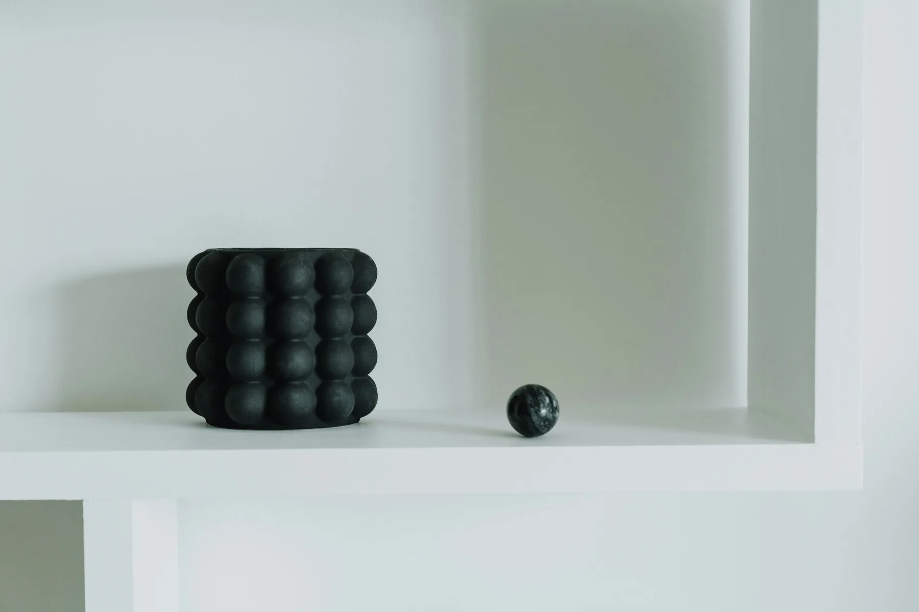 Rouleau et balle de massage posés sur une étagère blanche