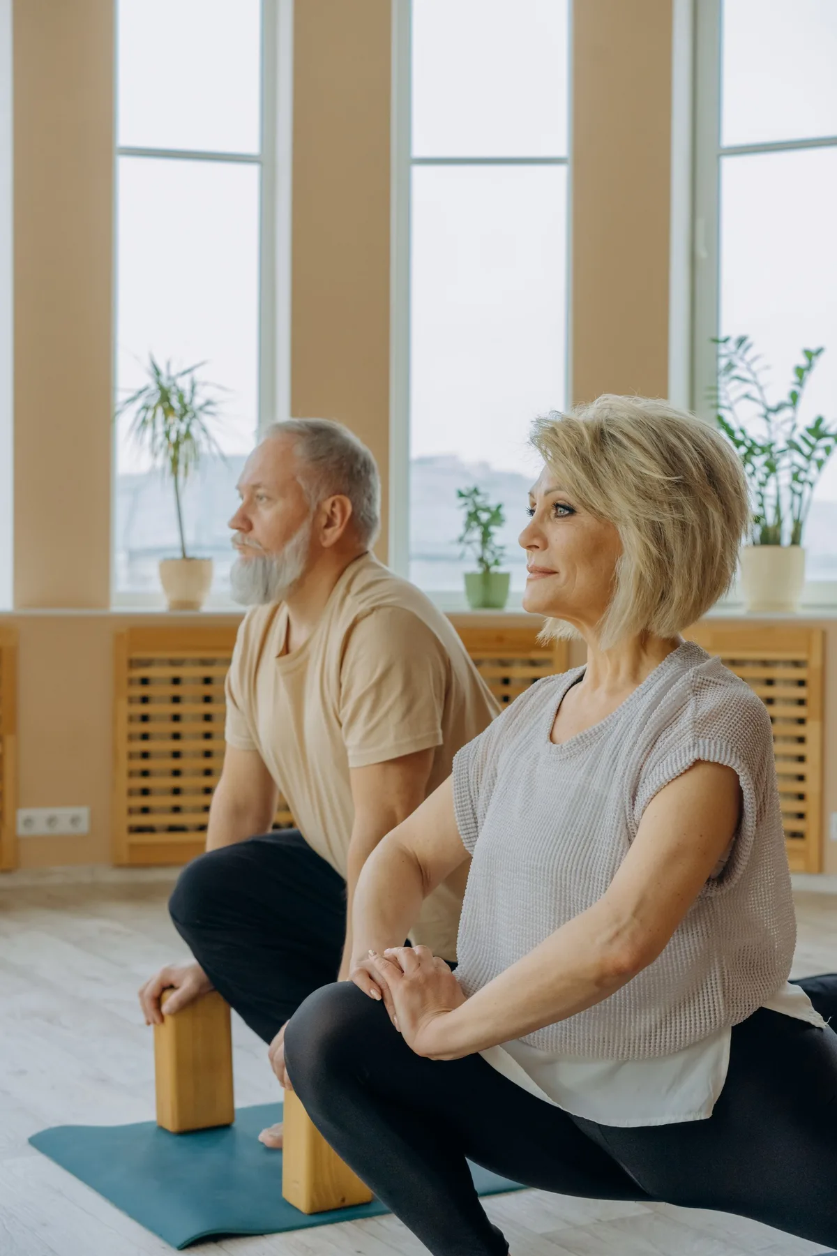 Couple de seniors en fente sur des tapis, avec des briques