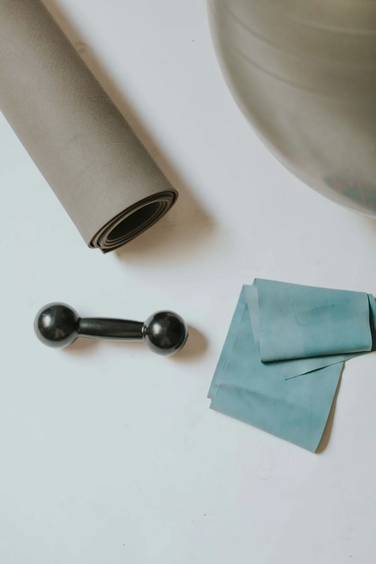 Tapis roulé, petit haltère et élastique sur fond clair