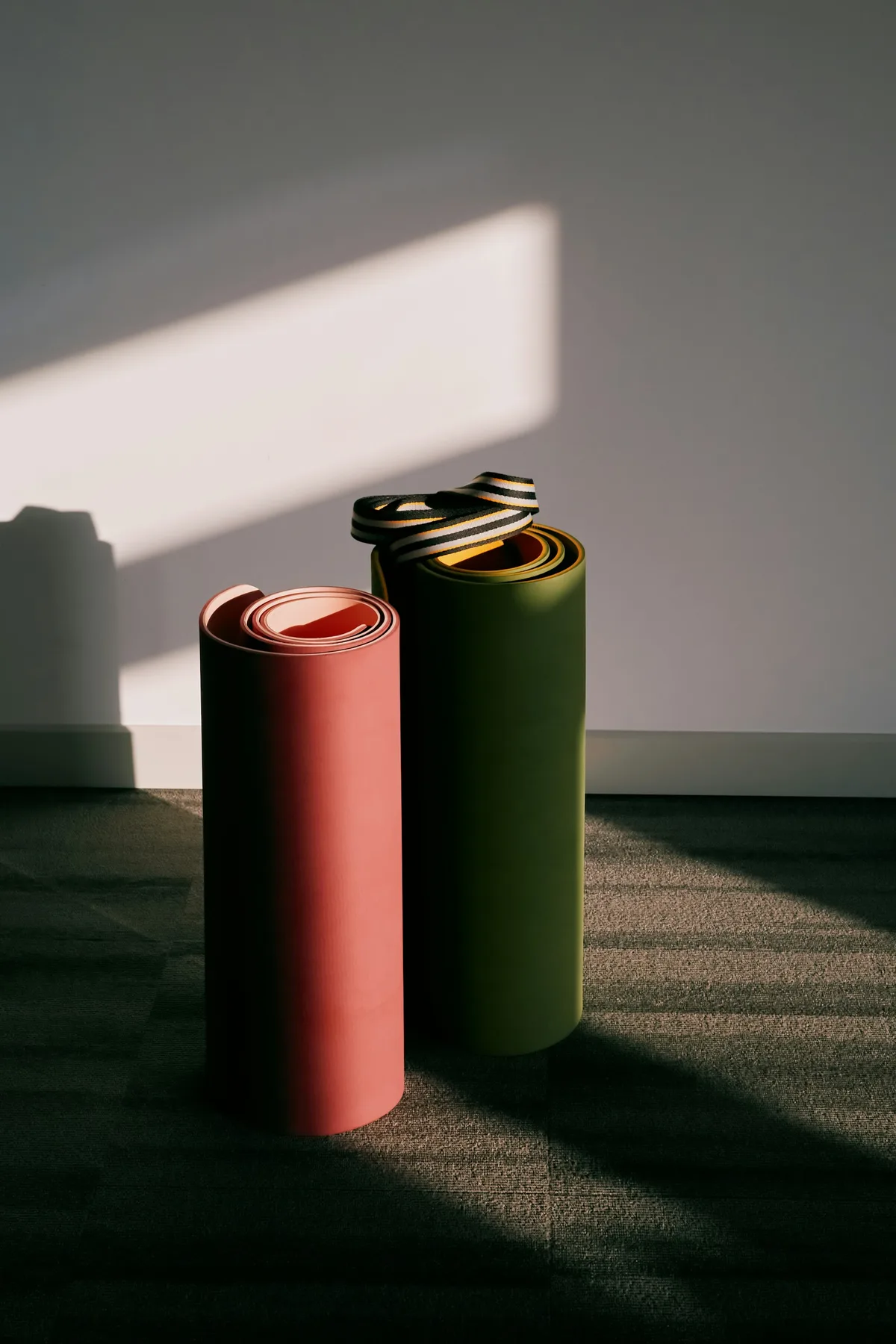 Deux tapis roulés, rouge et vert, dans la lumière